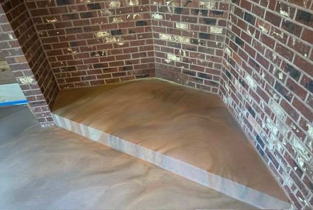 A corner of a room with a brick wall and a wooden floor.