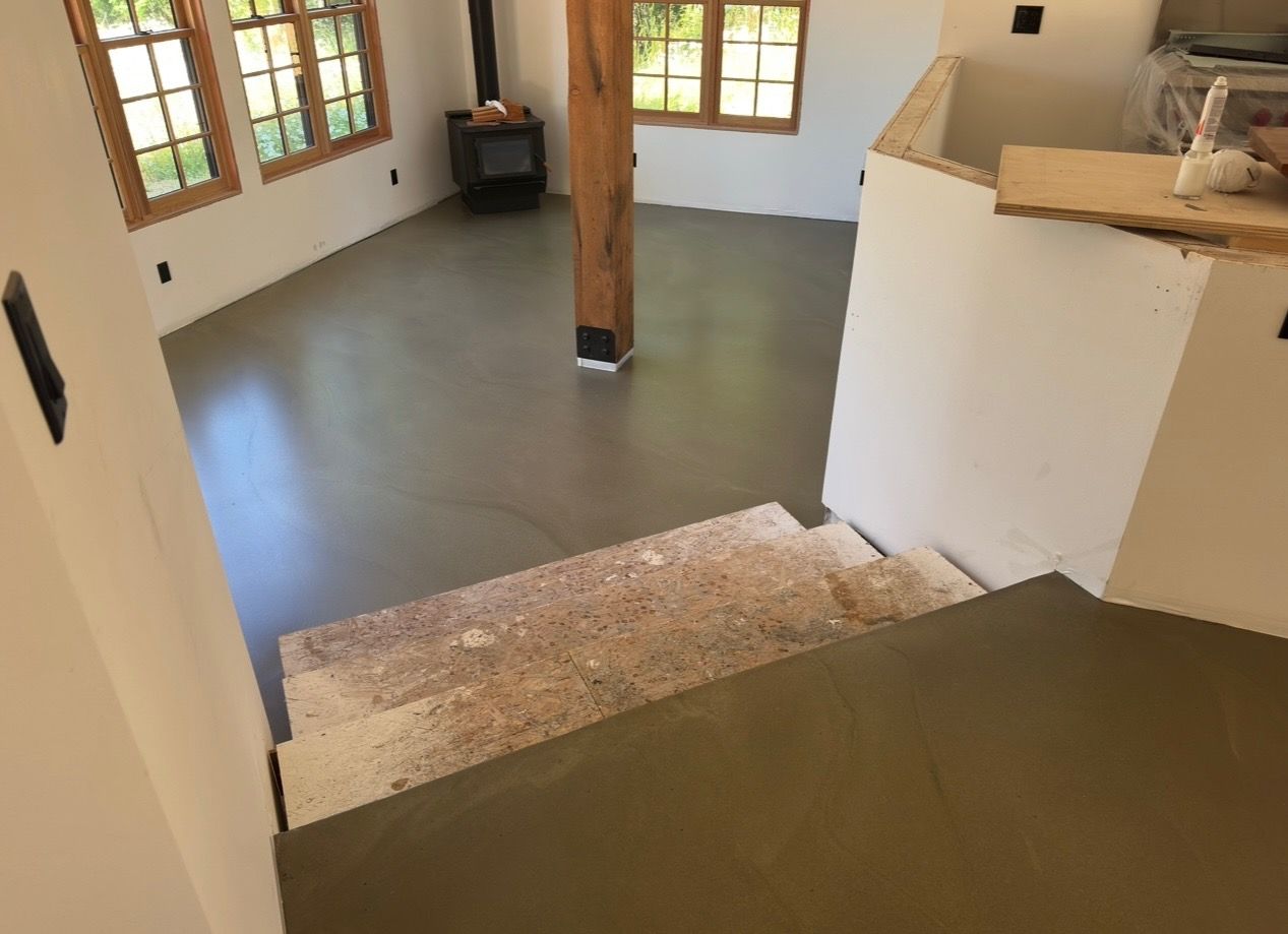 A room with a concrete floor and stairs in it.