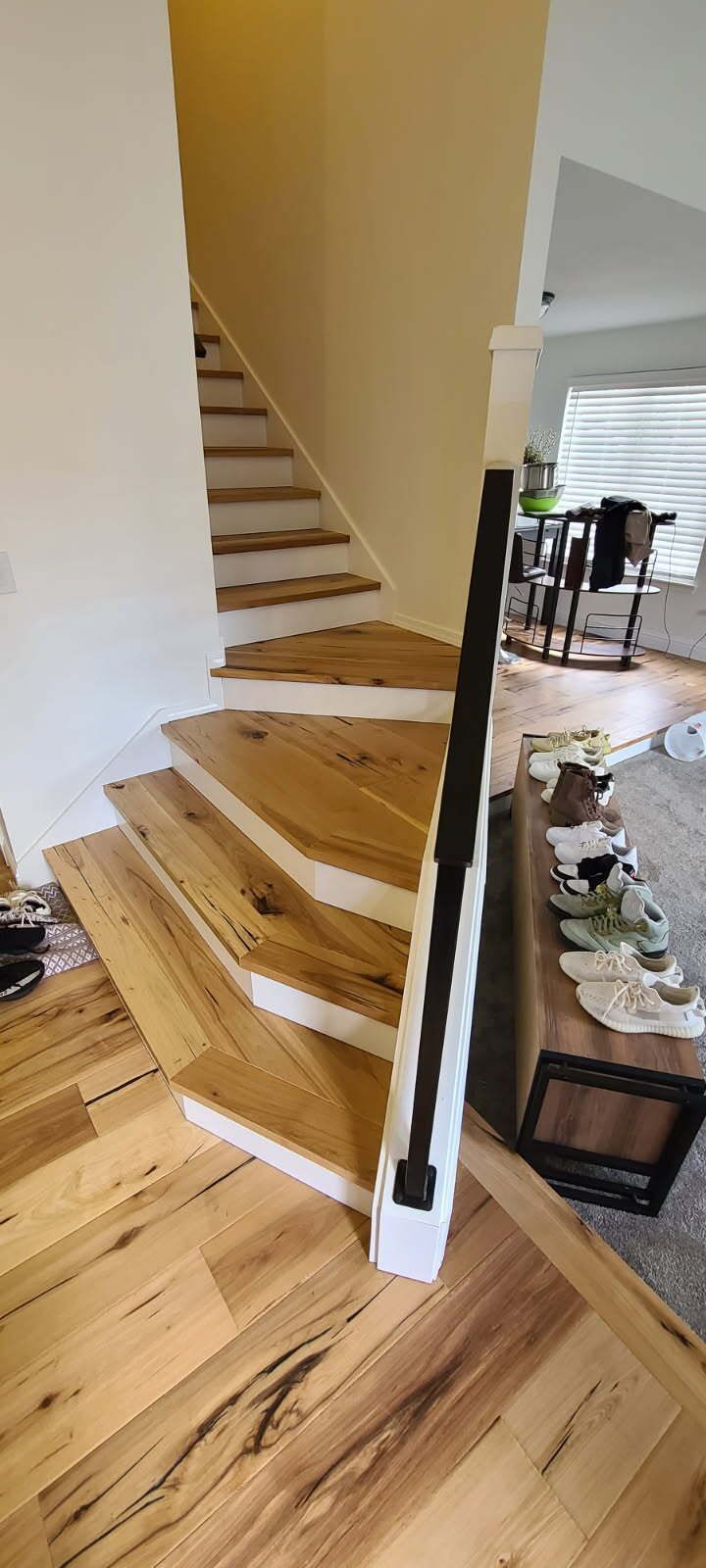 A wooden staircase with a black railing in a living room.