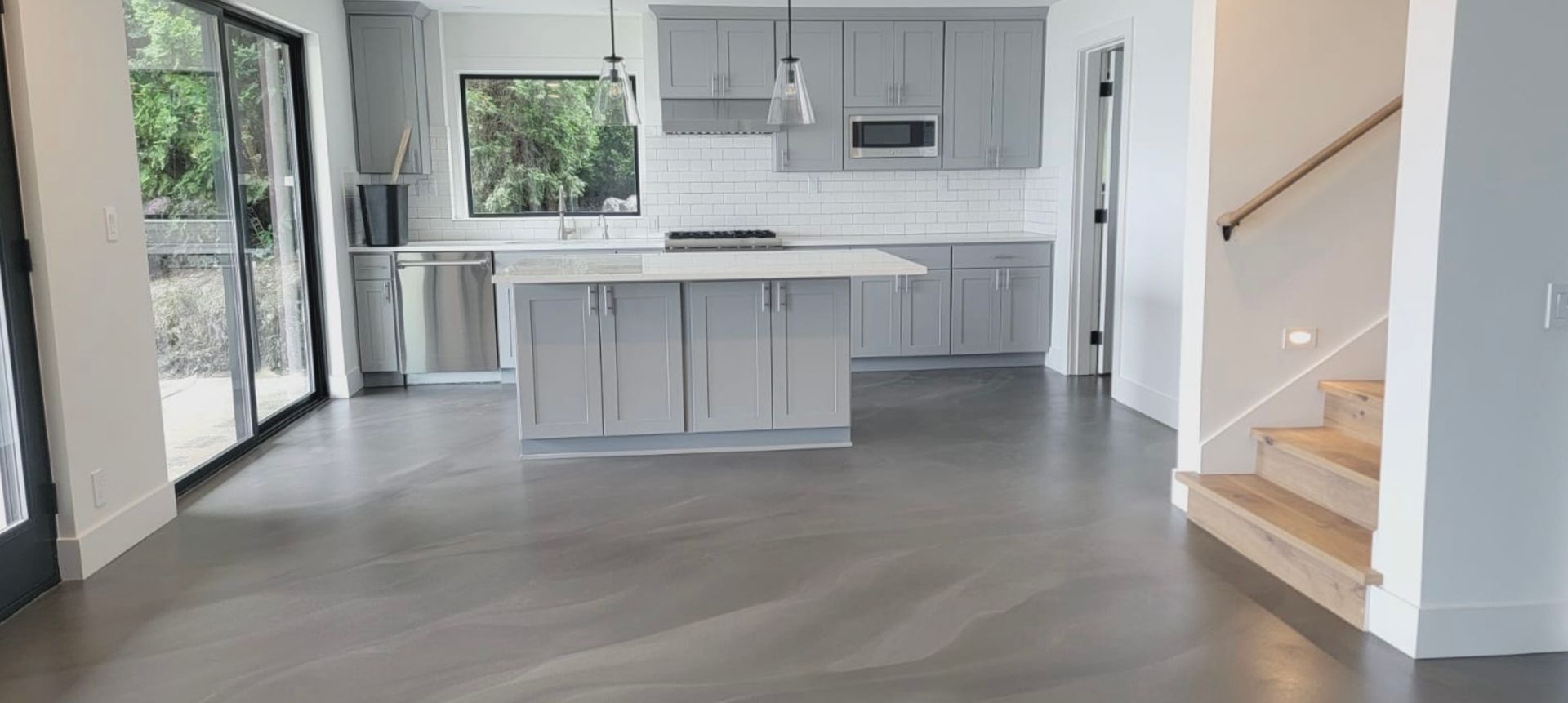 A kitchen with a large island and stairs in a house.