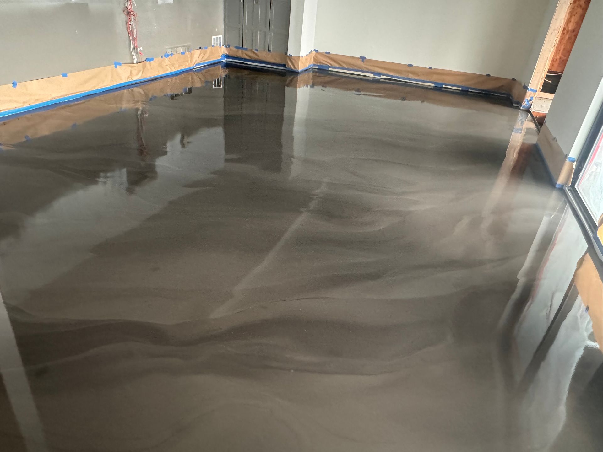A room with a shiny metallic floor and a reflection of a building in the floor.