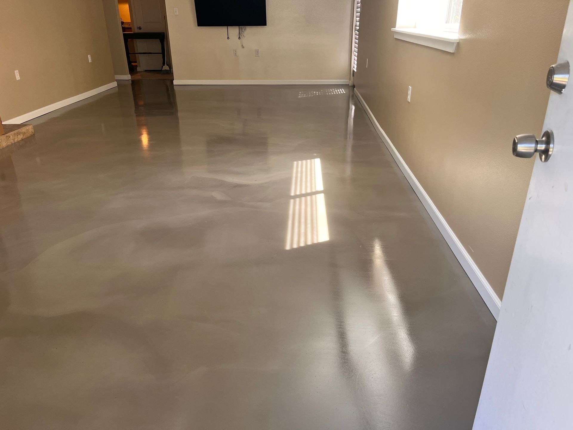 A living room with a shiny metallic floor and a flat screen tv.