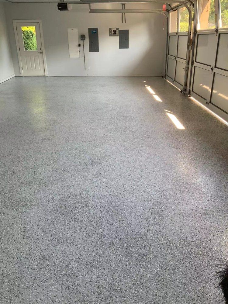 A large empty garage with a gray floor and white walls.