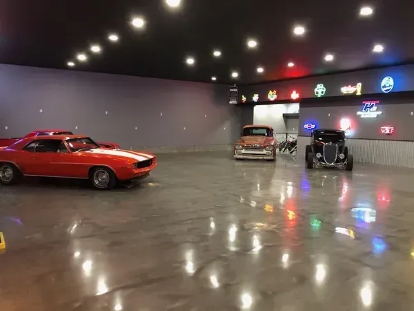 A red car is parked in a garage with other cars.