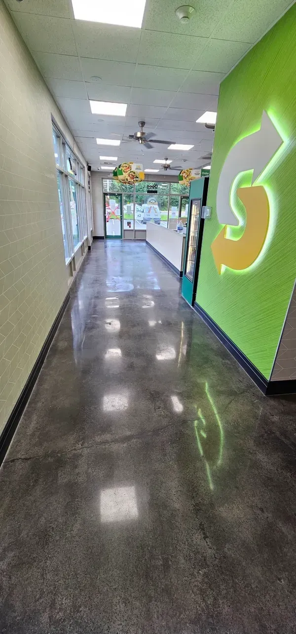 A long hallway in a building with a subway logo on the wall.