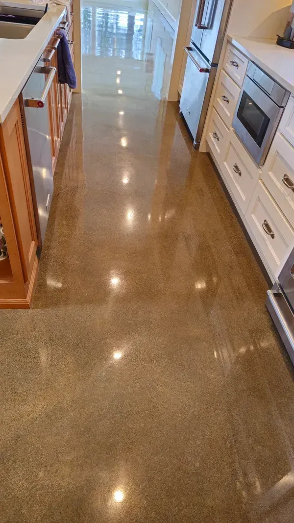 A kitchen with a shiny concrete floor and stainless steel appliances.