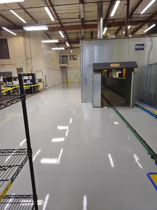 A large warehouse with a gray floor and a gray door.