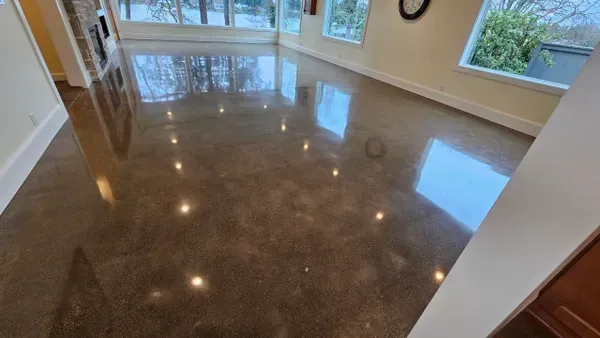 A living room with a shiny concrete floor and a large window.