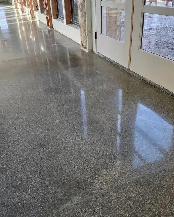 A hallway with a shiny concrete floor and white doors.