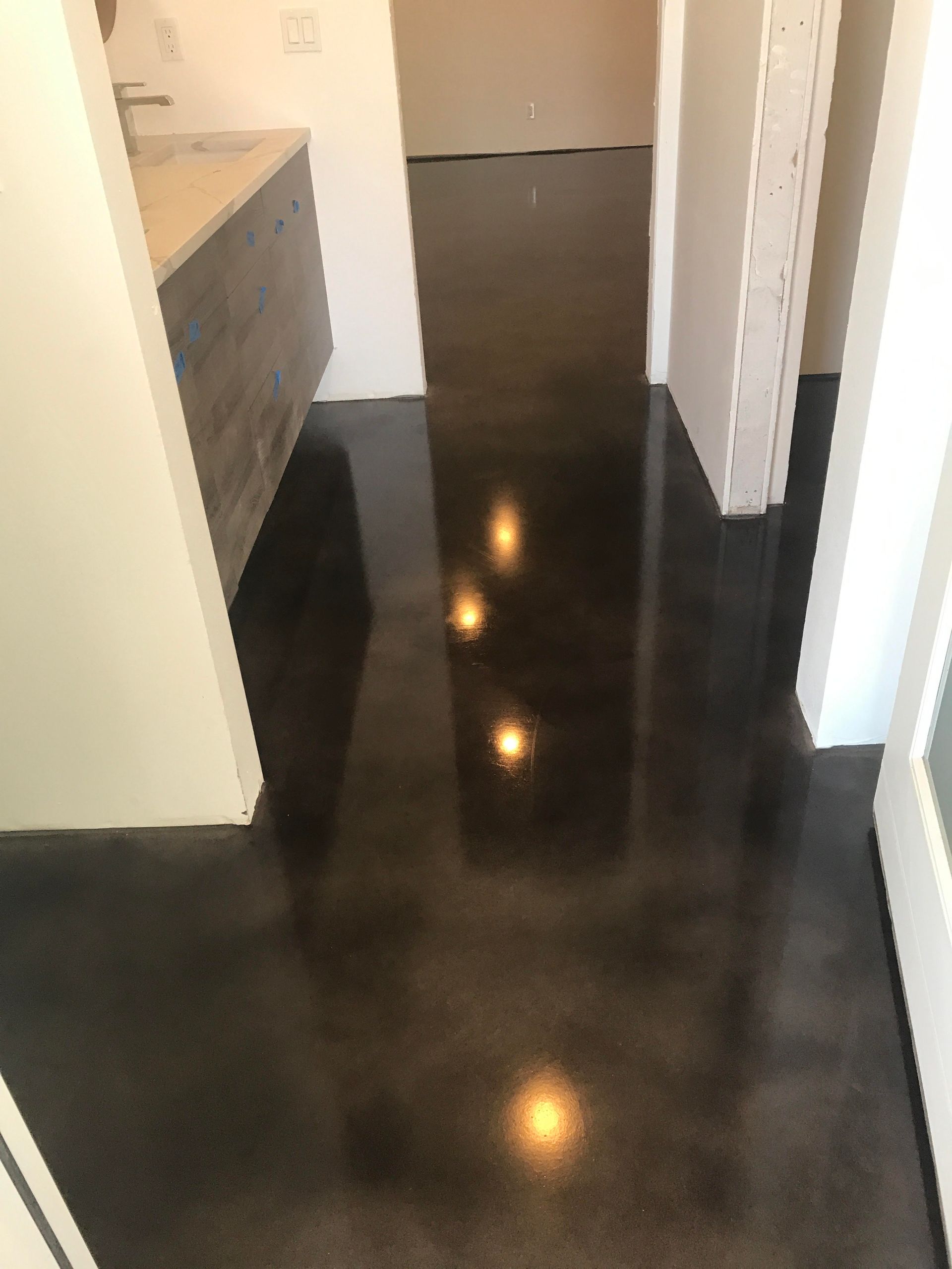 A hallway with a black concrete floor and a sink.