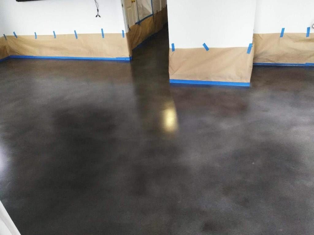 A concrete floor in a room with blue tape on the walls
