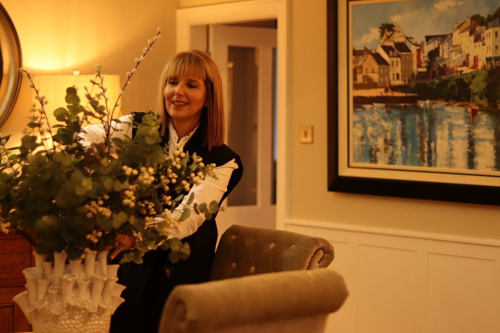 A woman is sitting in a chair holding a vase of flowers.