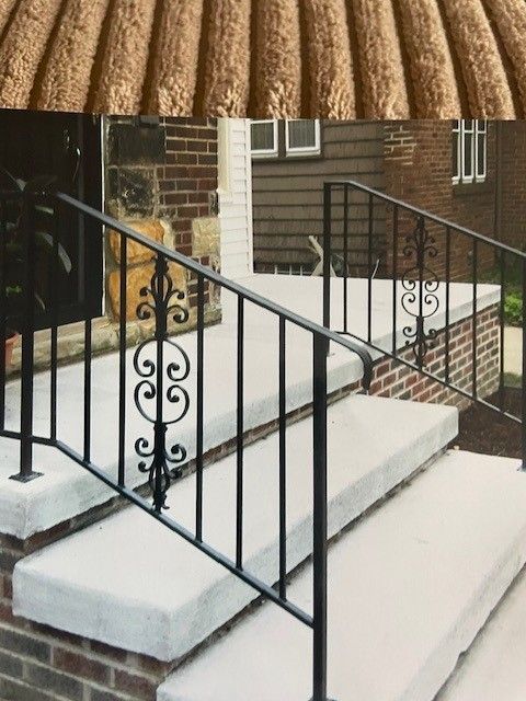 Black metal handrails along white concrete steps outside a brick house.
