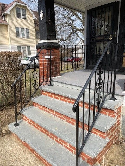 Brick front steps with black iron railings leading to a porch entrance