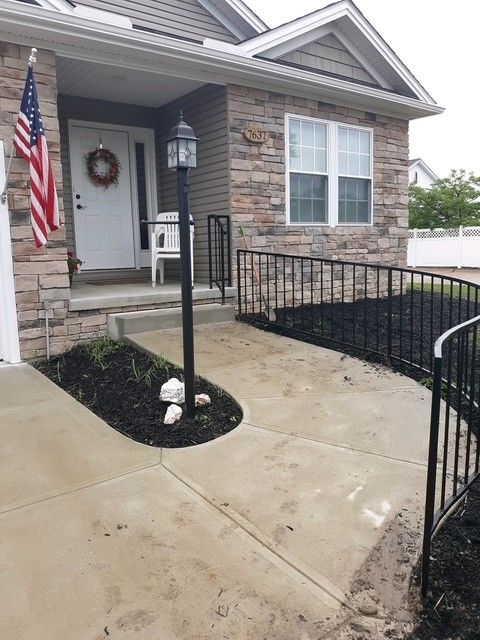 Front porch with American flag, stone facade, and wheelchair-accessible ramp leading to the entrance