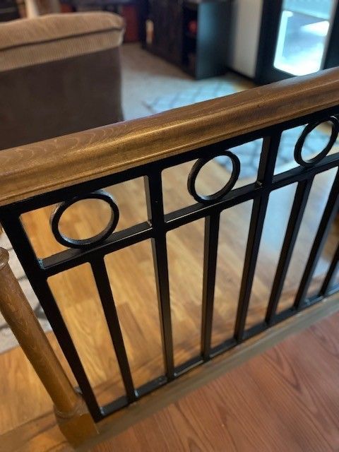 Black metal safety gate with circular accents in a home interior on a hardwood floor