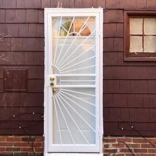 White metal security door with fanlight design on a brown house exterior