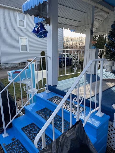 Blue decorated front porch with white railings, steps, and winter holiday accents