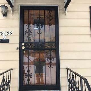 Black metal security door with glass panes and pink curtains at a house entrance