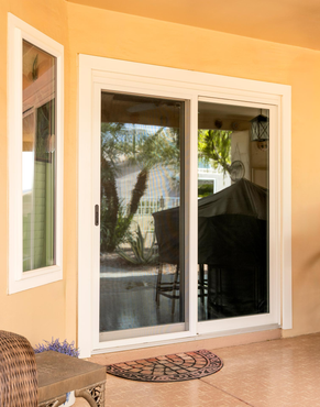 Sliding glass doors opening to a patio with potted plants and a covered grill