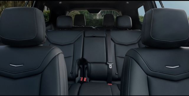 Back row seats of a black SUV.  Black leather seats are visible, with headrests and center armrest.