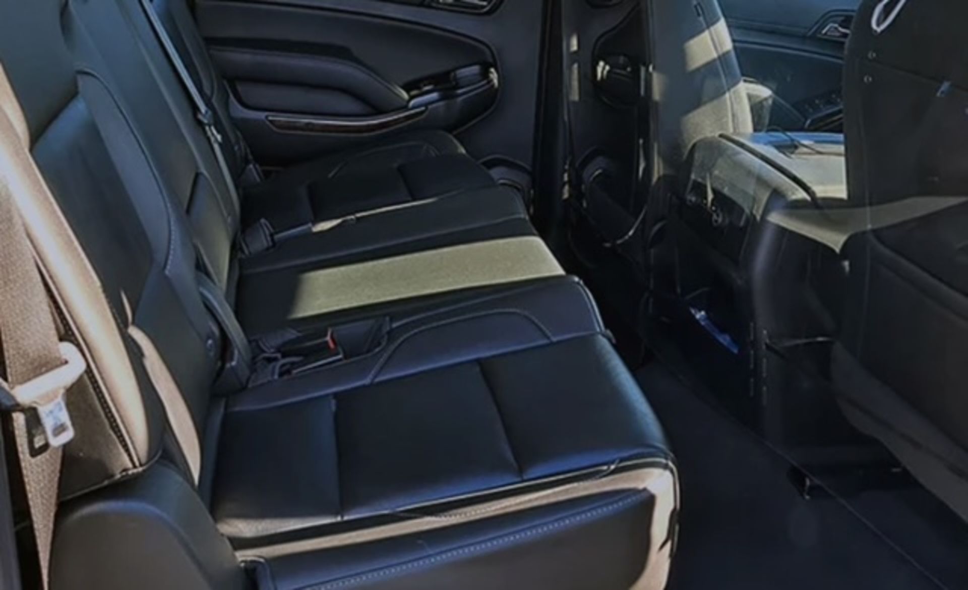 Black leather interior of a car, showing the rear seats and center console with cup holders.