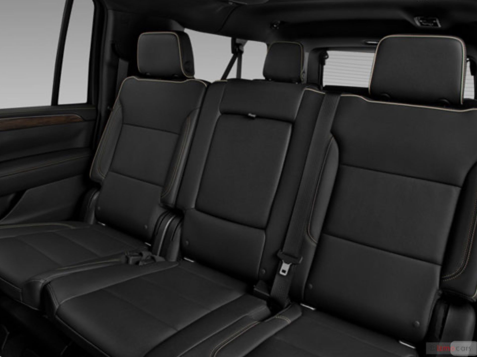 Black leather third-row seats in a vehicle, featuring headrests and seatbelts, with a window visible on the left.