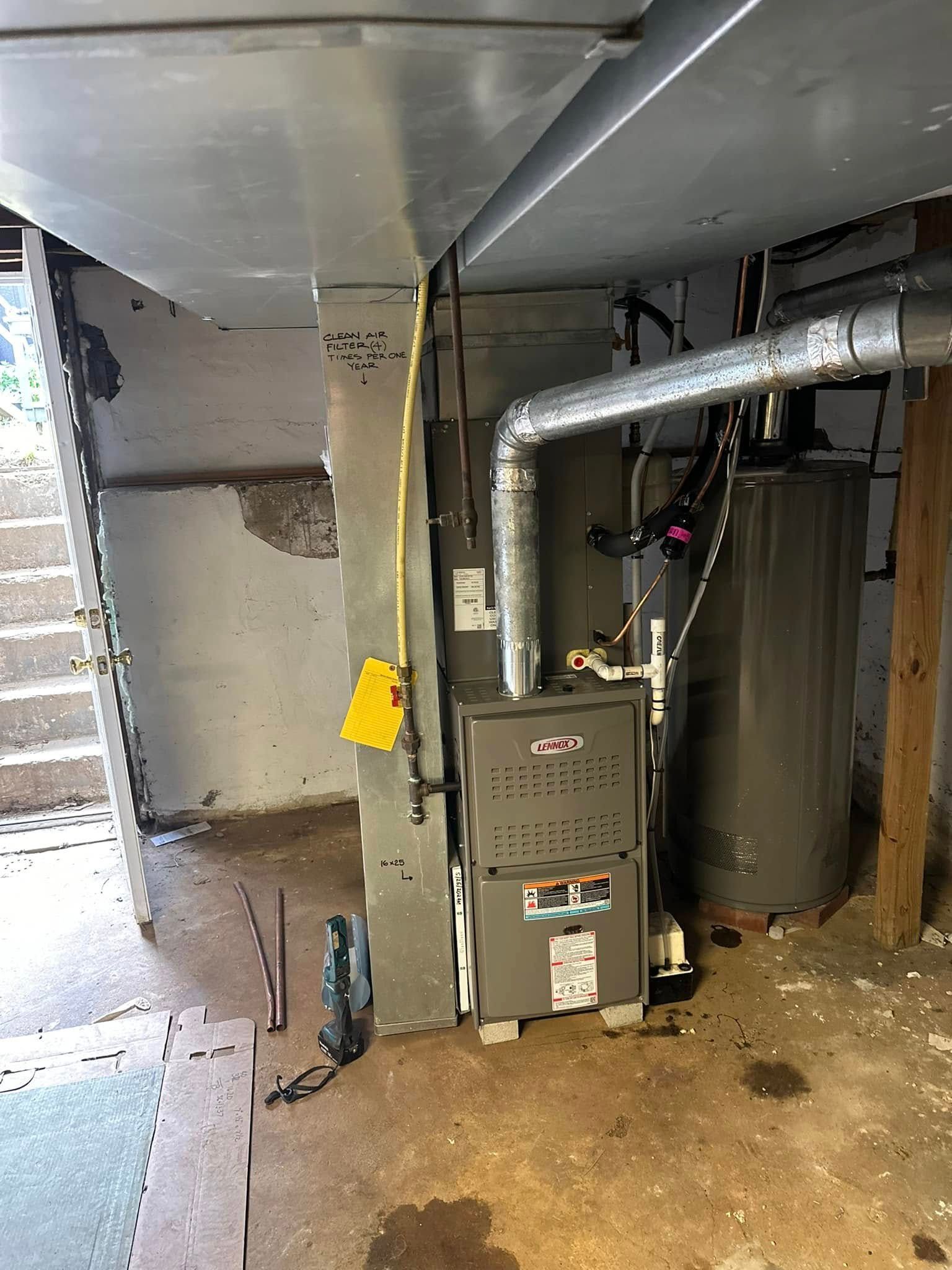 A furnace is sitting in a basement next to a water heater.
