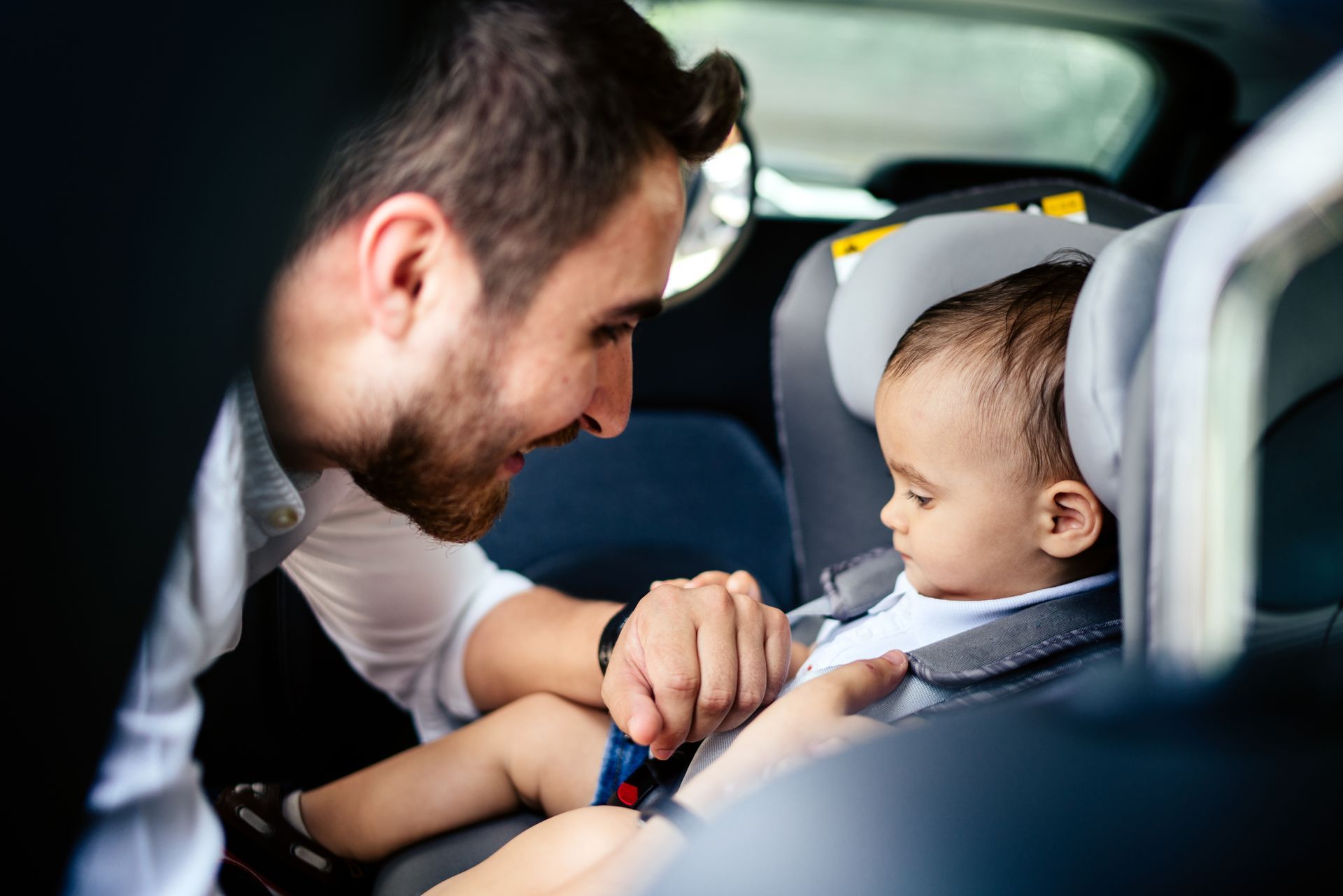 a man is putting a baby in a car seat .