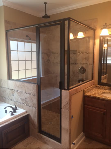 A bathroom with a dark-framed glass shower enclosure situated between a tiled soaking tub and a wooden vanity.