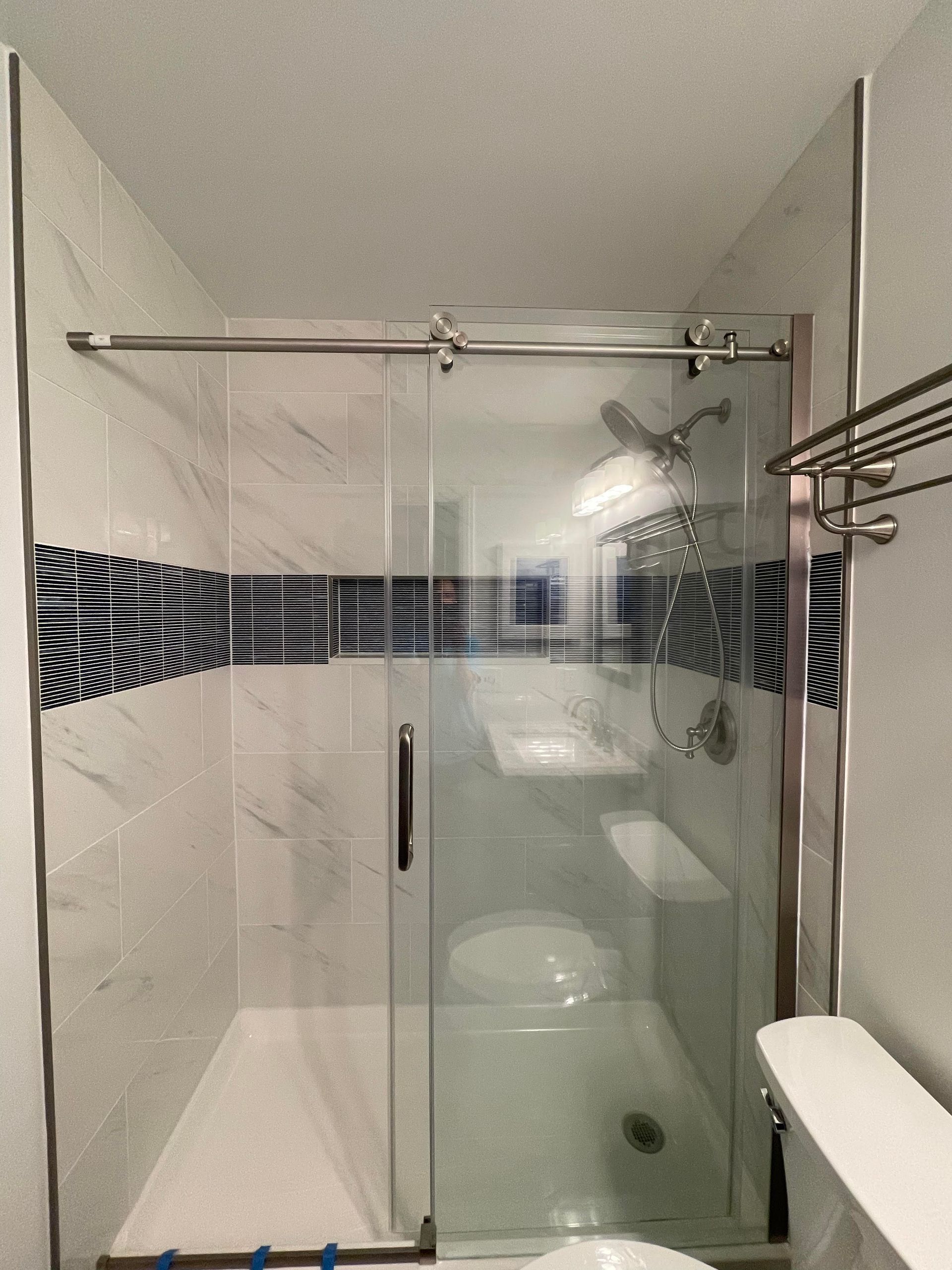 A bathroom with a sliding glass shower door.