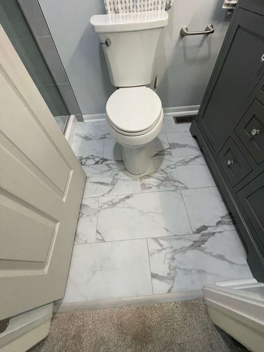 A bathroom with a toilet , sink , and marble floor.