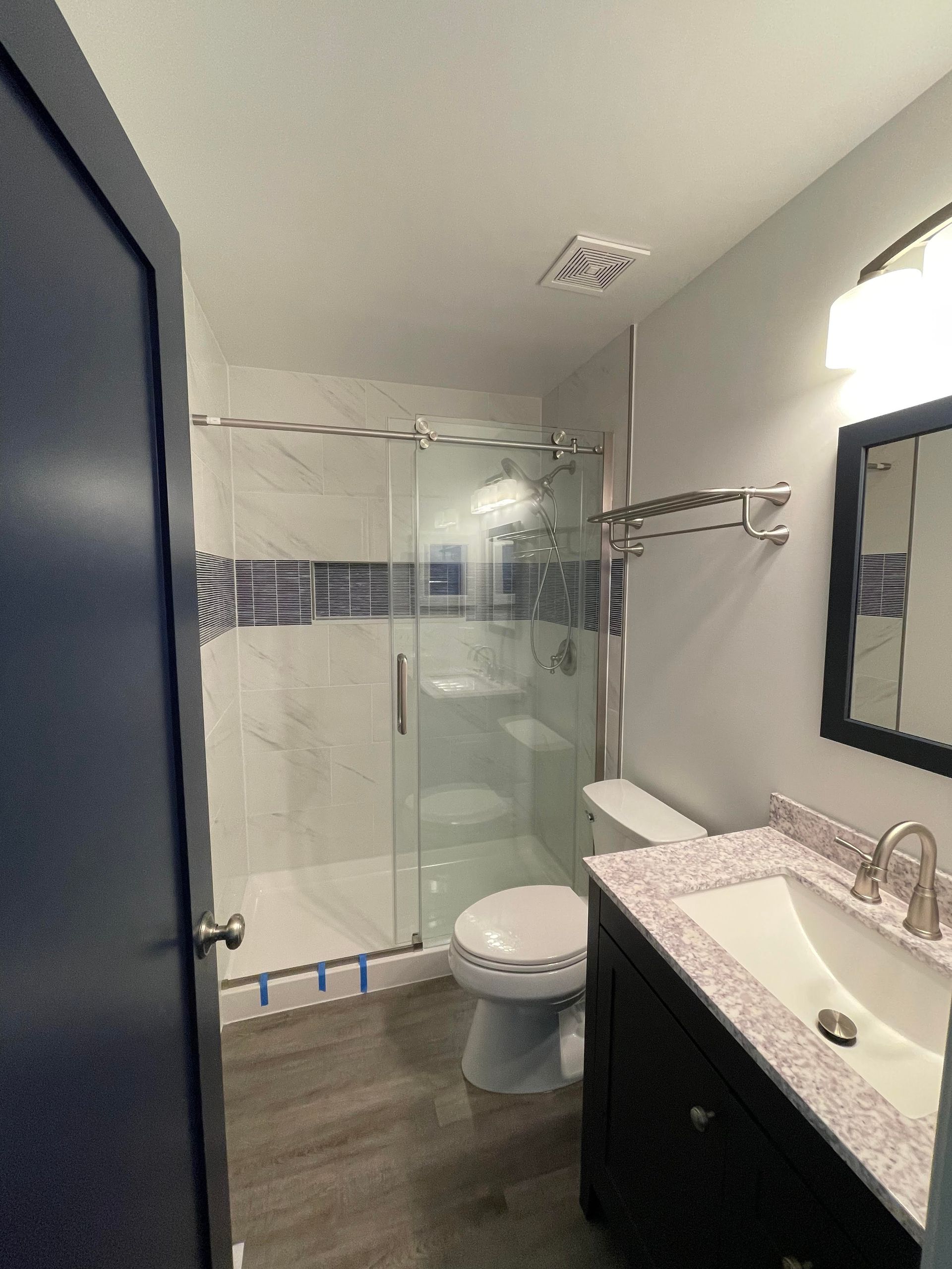 A bathroom with a toilet, sink, shower, and mirror.