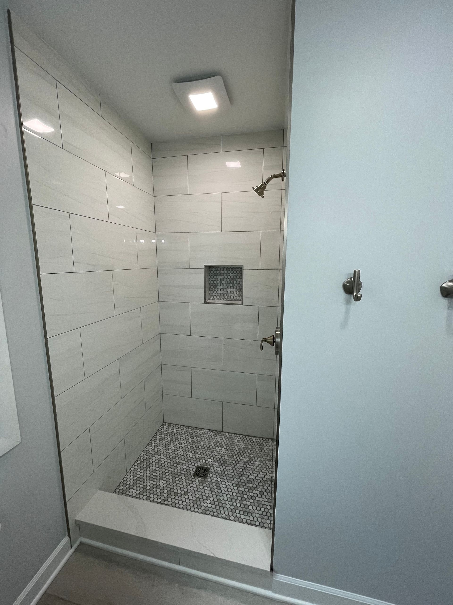 A bathroom with a walk in shower and a shower head.