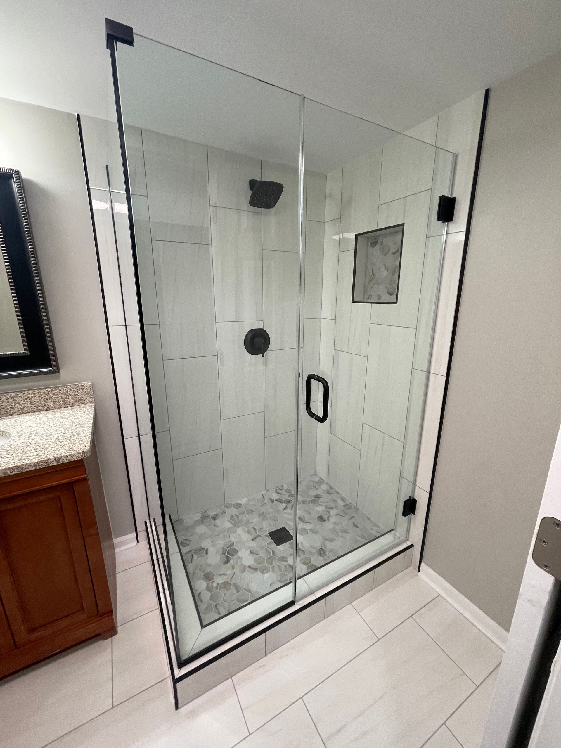A bathroom with a walk in shower and a sink.