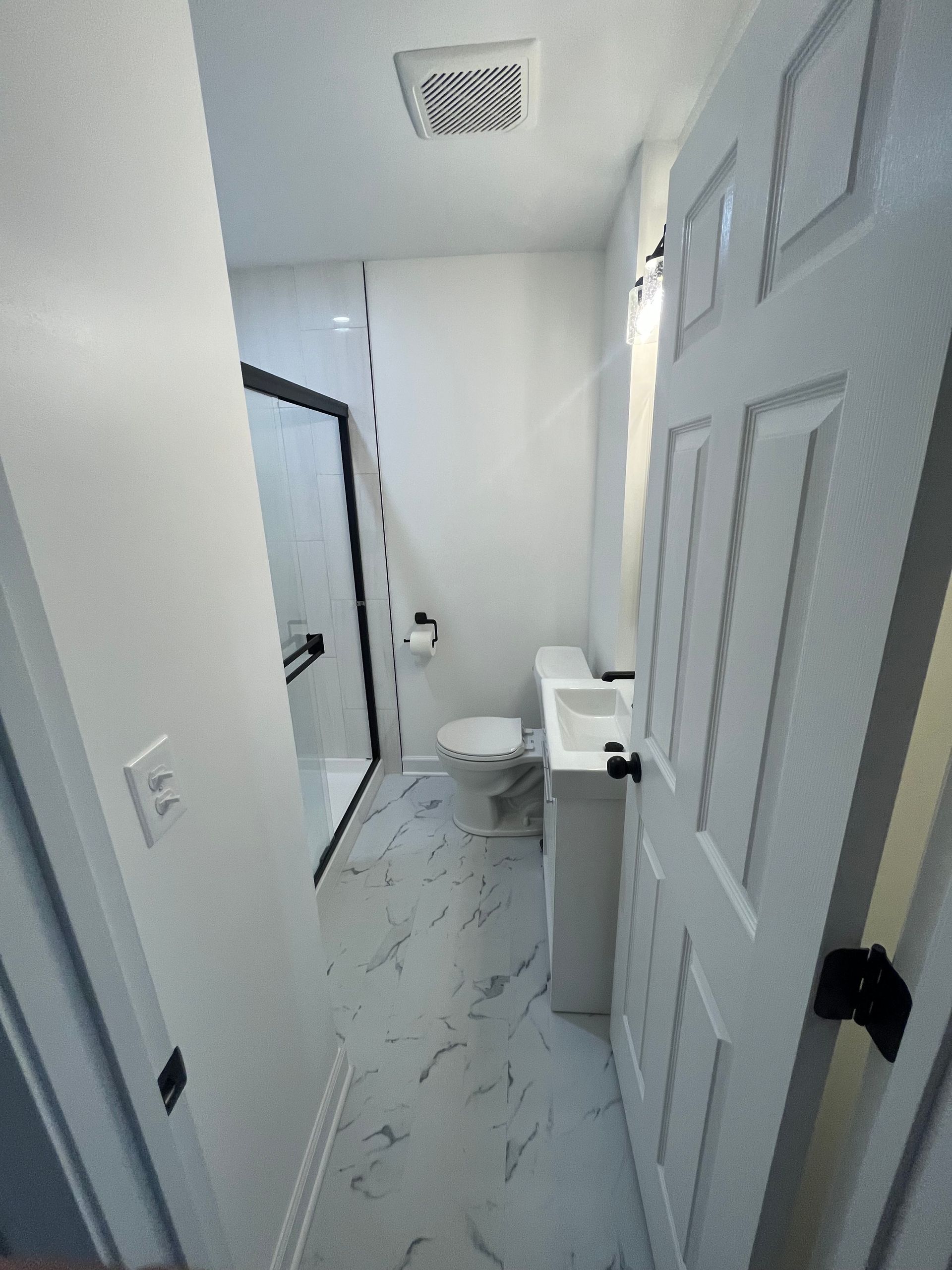 A bathroom with a toilet , sink and shower.