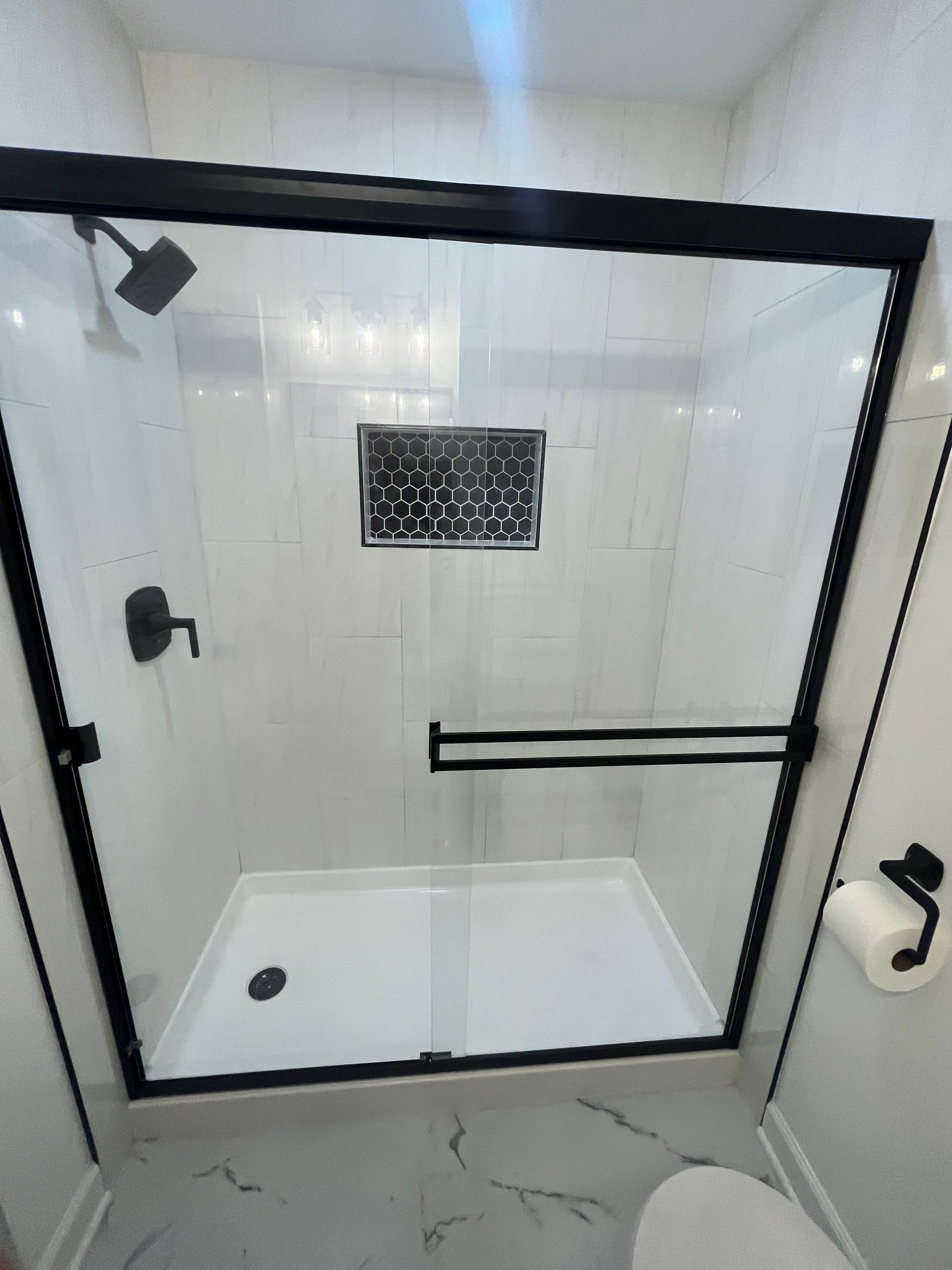 A bathroom with a sliding glass shower door