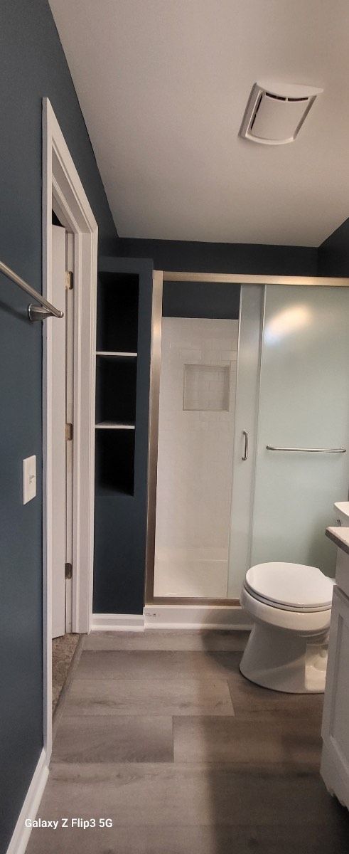 A bathroom with a toilet , sink and shower stall.