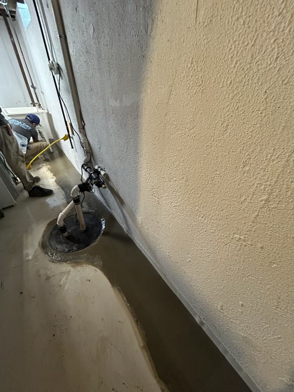 Basement with light blue painted floor, wooden staircase, and exposed ceiling beams.