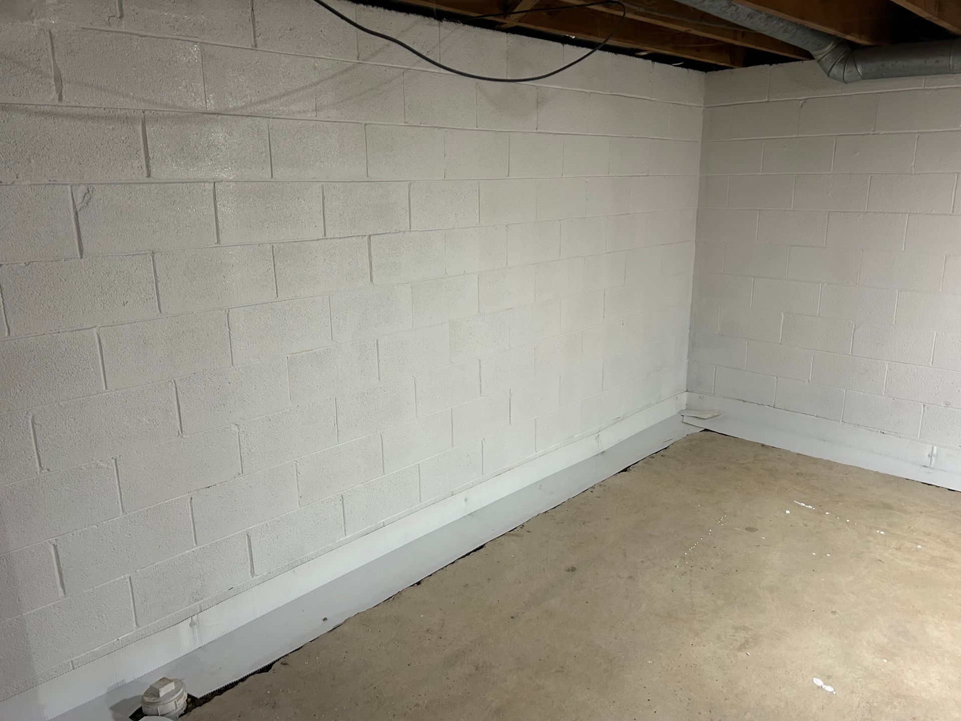 Garage interior with concrete floor, shelving, a refrigerator, and stairs.
