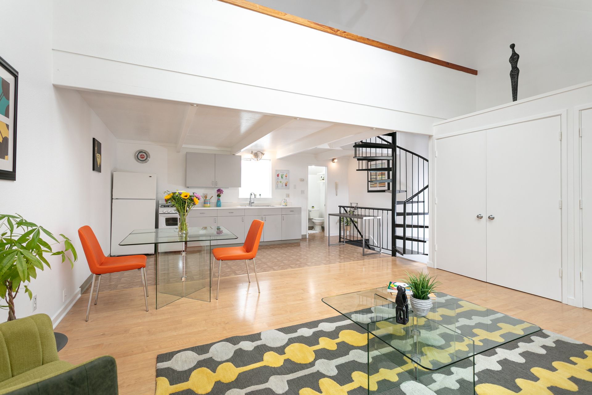 A living room with a spiral staircase and a table and chairs