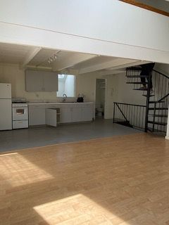 An empty kitchen with a spiral staircase leading to the second floor.