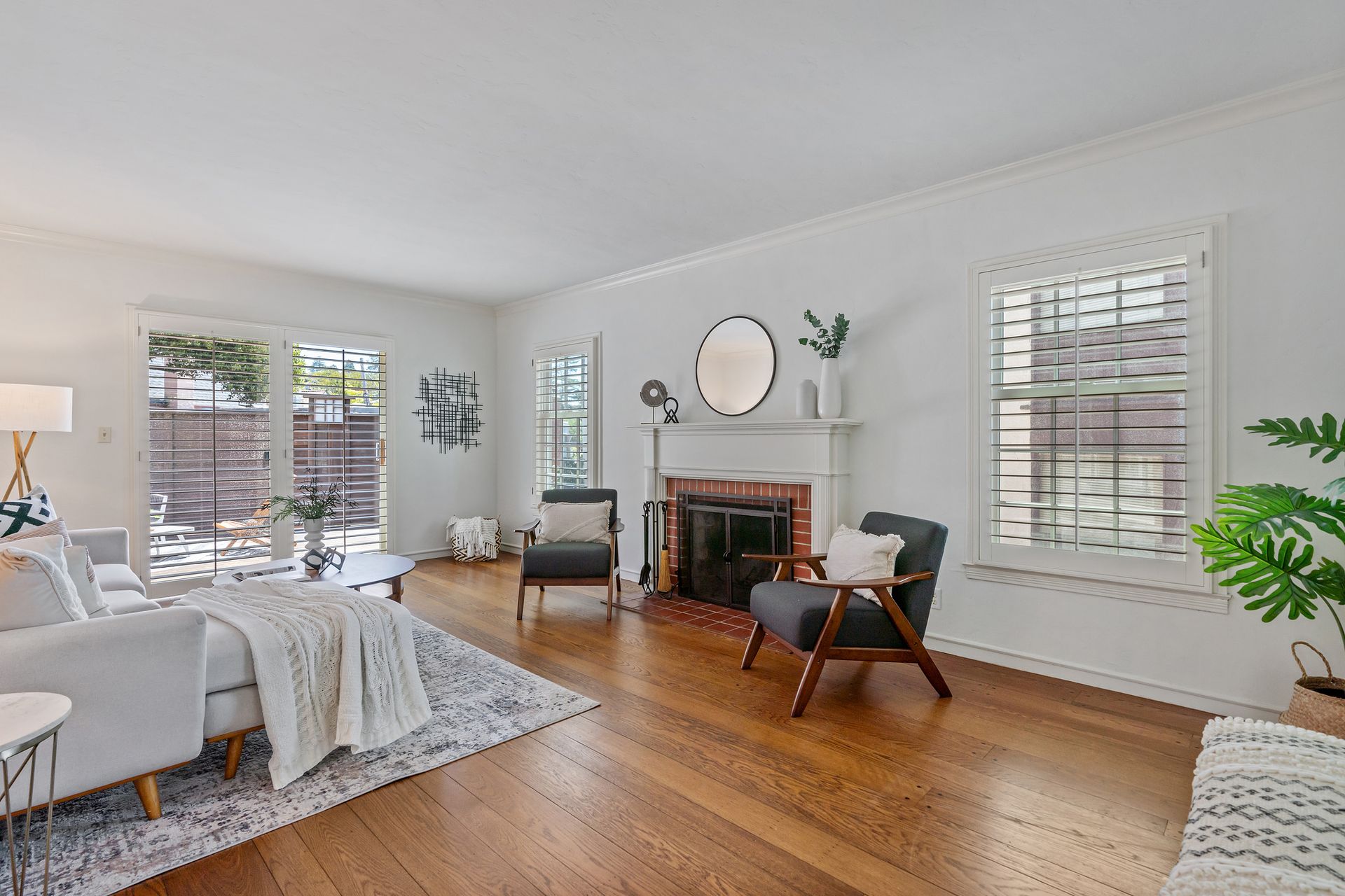 A living room with hardwood floors , a couch , chairs and a fireplace.
