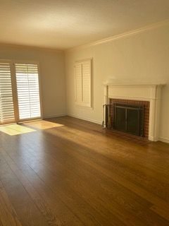 An empty living room with hardwood floors and a fireplace.