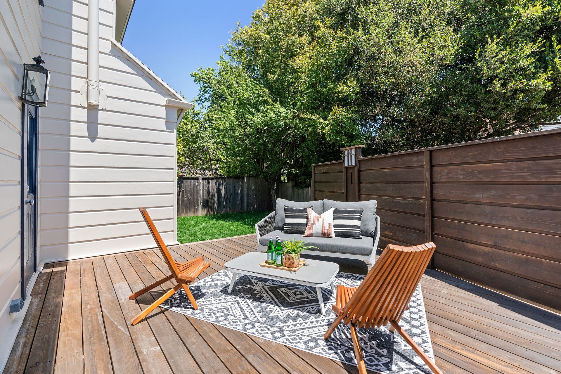 There is a wooden deck with a couch and chairs on it.