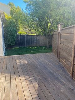 A wooden deck with a wooden fence in the backyard of a house.