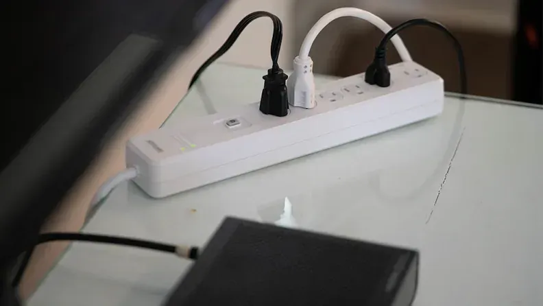 a power strip is sitting on a glass table next to a hard drive .