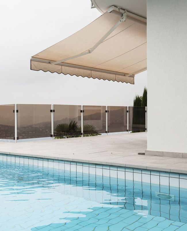 Plain coloured, motorised awnings installed near the swimming pool