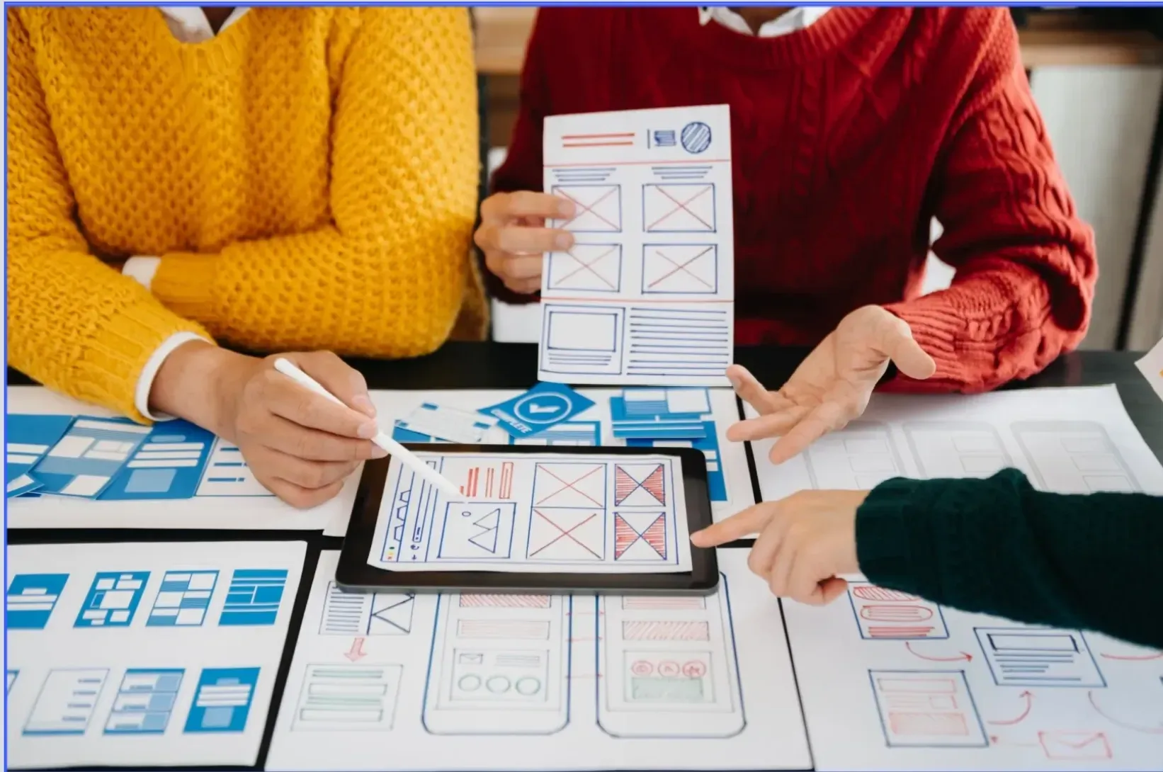 Lead Peak Media team of three reviewing documents around a tablet during a Tucson SEO strategy session.