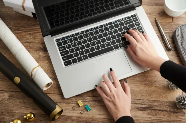 Hands typing on a laptop keyboard on a desk with rolled paper and paper clips, representing Tucson web design.